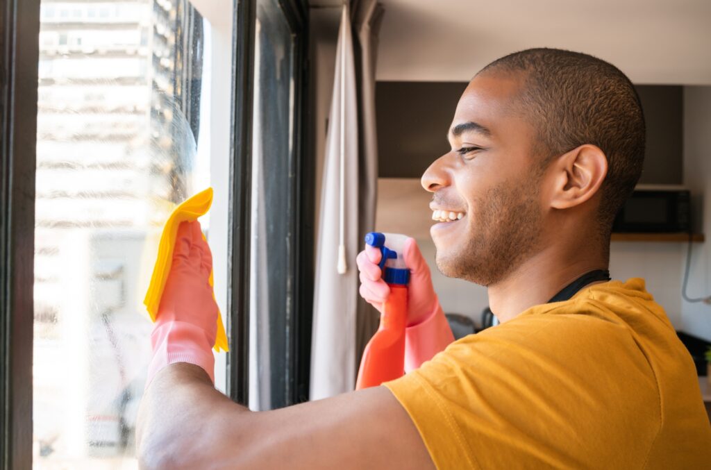 A young man cleaning a window using a Microfiber Cloth